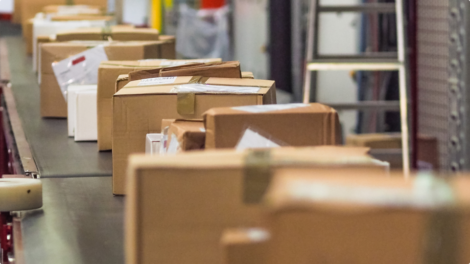 Packed boxes moving on a conveyer belt in warehouse.